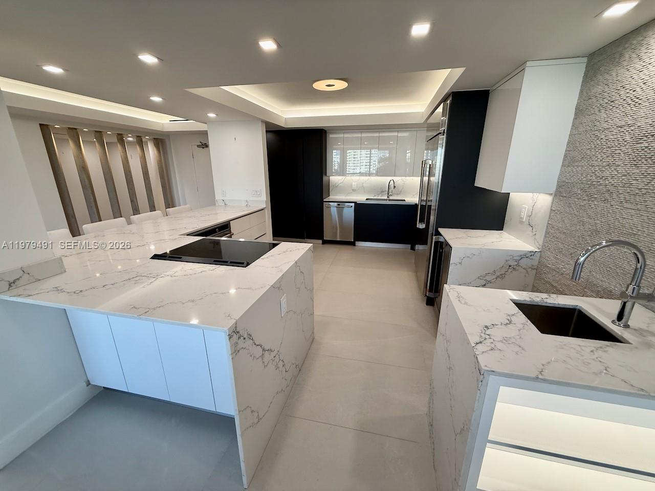 A modern kitchen features white marble countertops, dark cabinetry, and a large central island — 900 Bay Dr # 524, Miami Beach FL 33141, MIAMI BEACH, FL