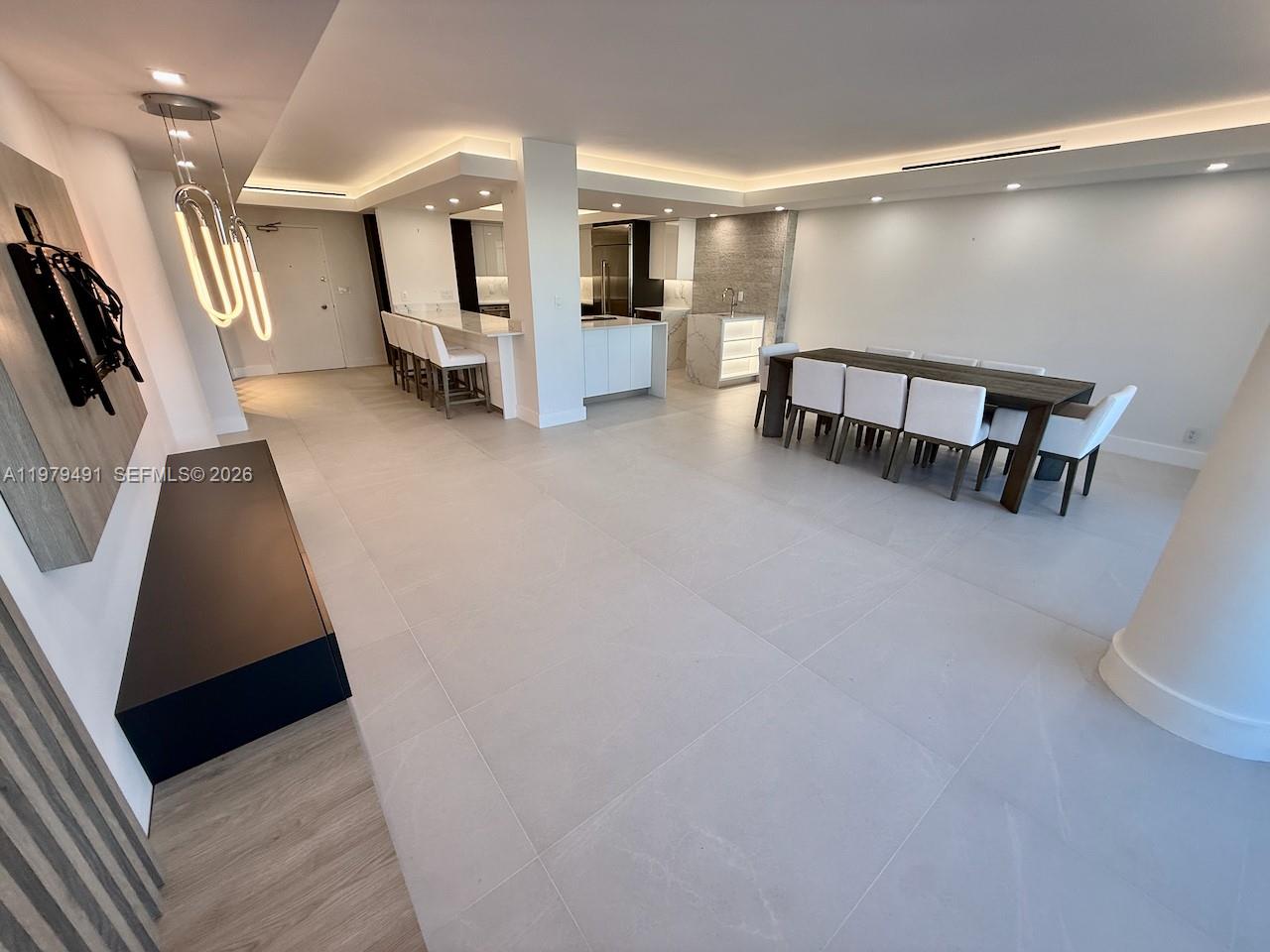 A modern open-concept living area features a kitchen with bar seating and a dining table — 900 Bay Dr # 524, Miami Beach FL 33141, MIAMI BEACH, FL