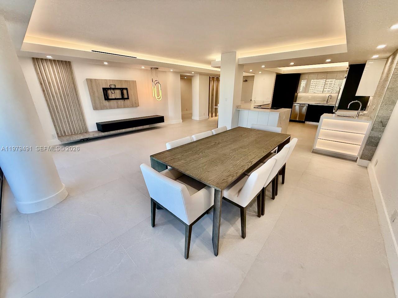A modern open-concept dining area features a wooden table, white chairs, and recessed lighting — 900 Bay Dr # 524, Miami Beach FL 33141, MIAMI BEACH, FL