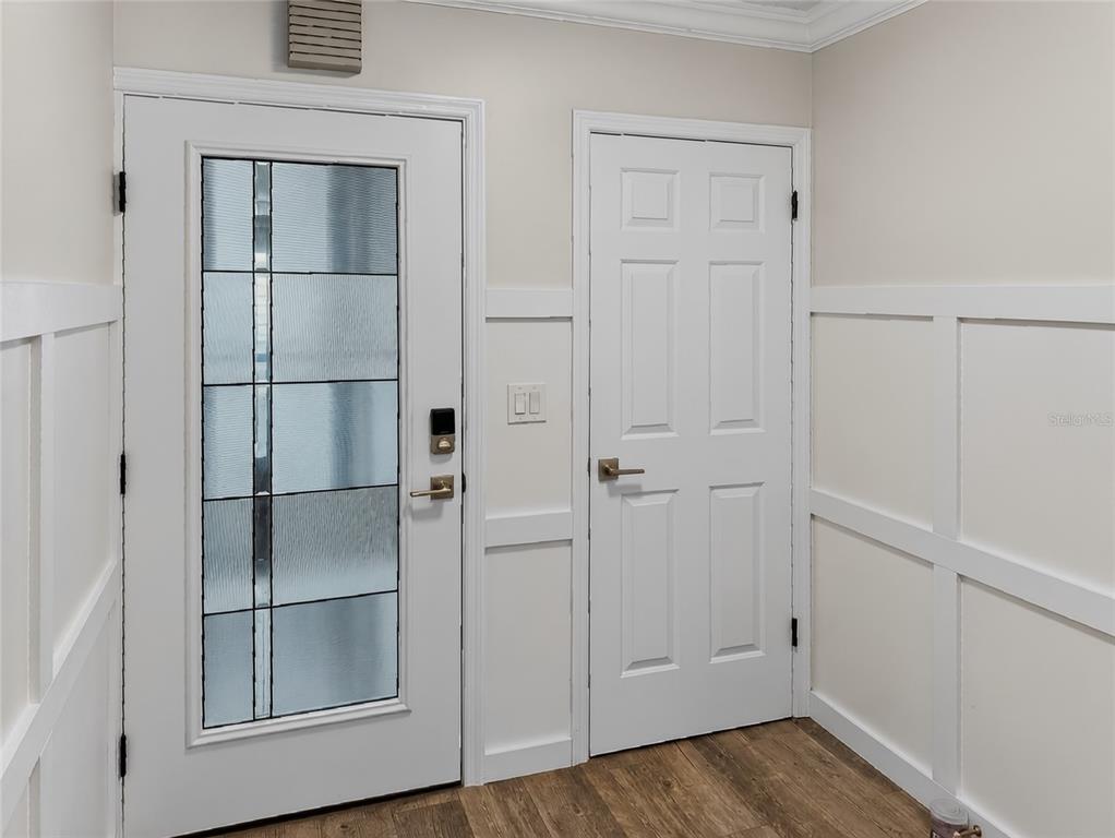 An entryway features a white front door with glass panels, a closet door, and wainscoting — 1111 N BAYSHORE BOULEVARD UNIT E3, CLEARWATER, FL