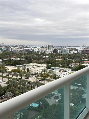 A high-angle view from a balcony overlooking a city skyline, trees, and a road — 10101 Collins Ave # 15D, Bal Harbour FL 33154, BAL HARBOUR, FL