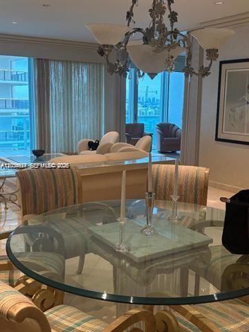 A glass-topped dining table with striped chairs sits in front of a living area — 10101 Collins Ave # 15D, Bal Harbour FL 33154, BAL HARBOUR, FL