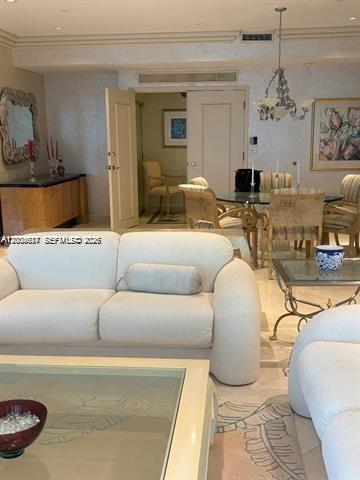 A living room features a white sofa, a glass coffee table, and a dining area — 10101 Collins Ave # 15D, Bal Harbour FL 33154, BAL HARBOUR, FL