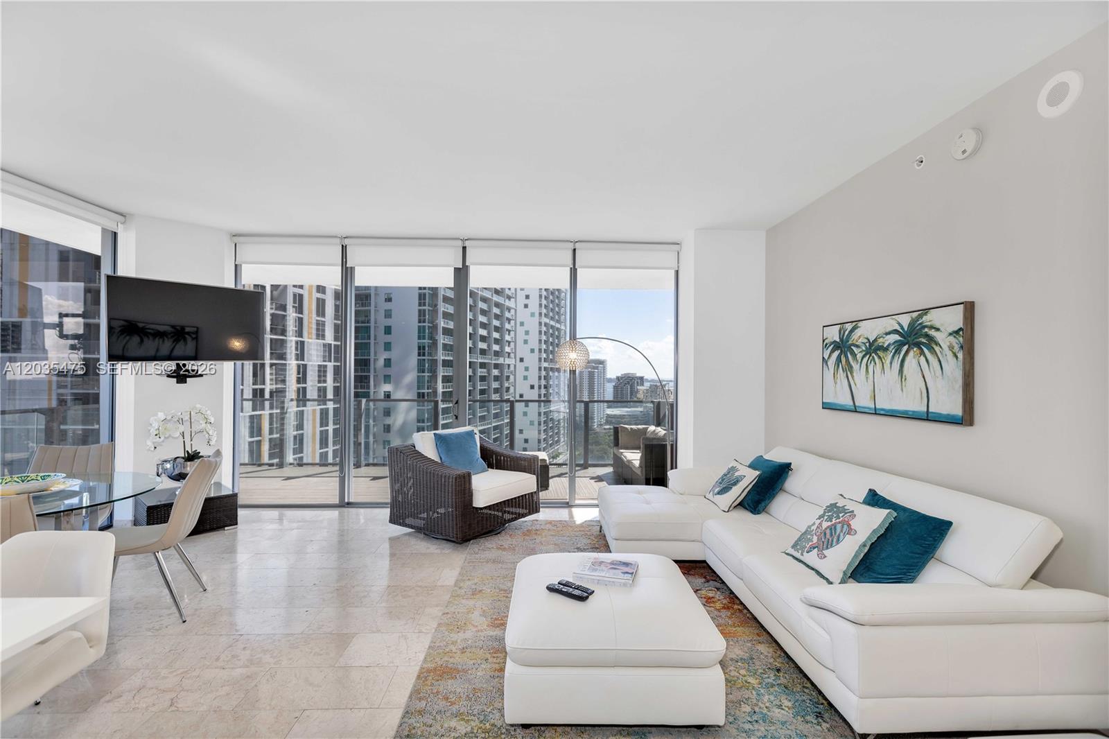 A modern living room features a white sectional sofa, marble floors, and floor-to-ceiling windows — 68 SE 6th St # 1611, Miami FL 33131, MIAMI, FL