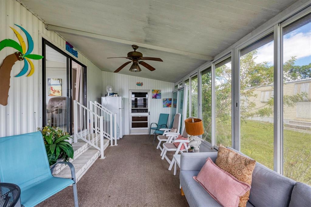 A sunroom features a ceiling fan, carpeted flooring, a sofa, chairs, and large windows — 7324 CANDACE LANE, PORT CHARLOTTE, FL