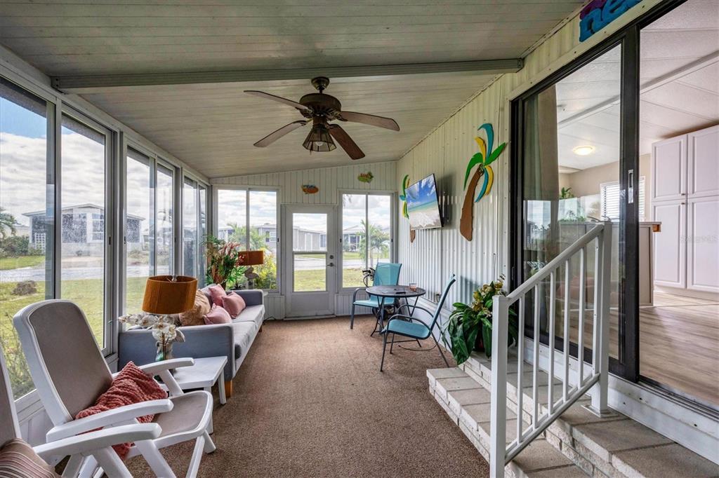 A sunroom features a ceiling fan, carpeted flooring, a sofa, and a sliding glass door — 7324 CANDACE LANE, PORT CHARLOTTE, FL