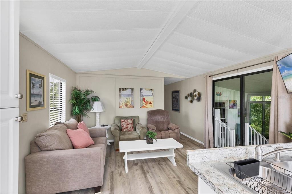 A living room features a sofa, two armchairs, a white coffee table, and sliding glass doors — 7324 CANDACE LANE, PORT CHARLOTTE, FL