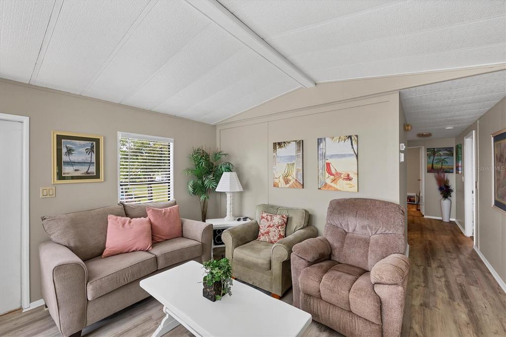 A living room features a sofa, two armchairs, a coffee table, and beach-themed wall art — 7324 CANDACE LANE, PORT CHARLOTTE, FL