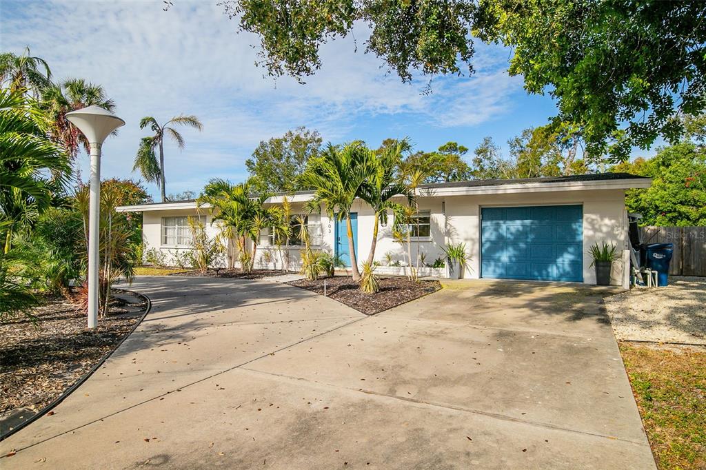A single-story house with a blue front door, a garage, and a concrete driveway — 703 WHITFIELD AVENUE, SARASOTA, FL