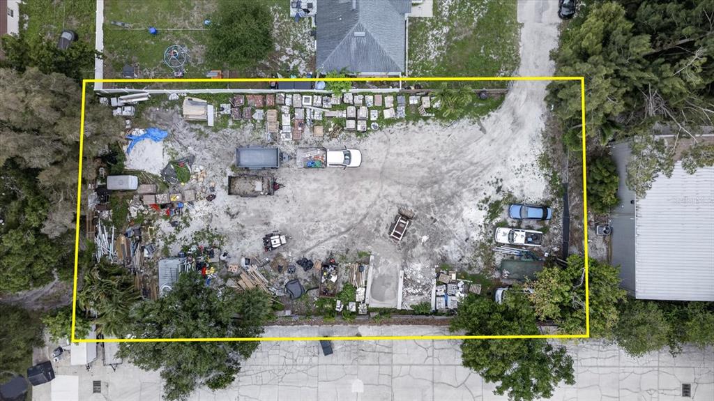An aerial view shows a rectangular lot with scattered debris, vehicles, and building materials — 6353 143RD AVENUE, CLEARWATER, FL