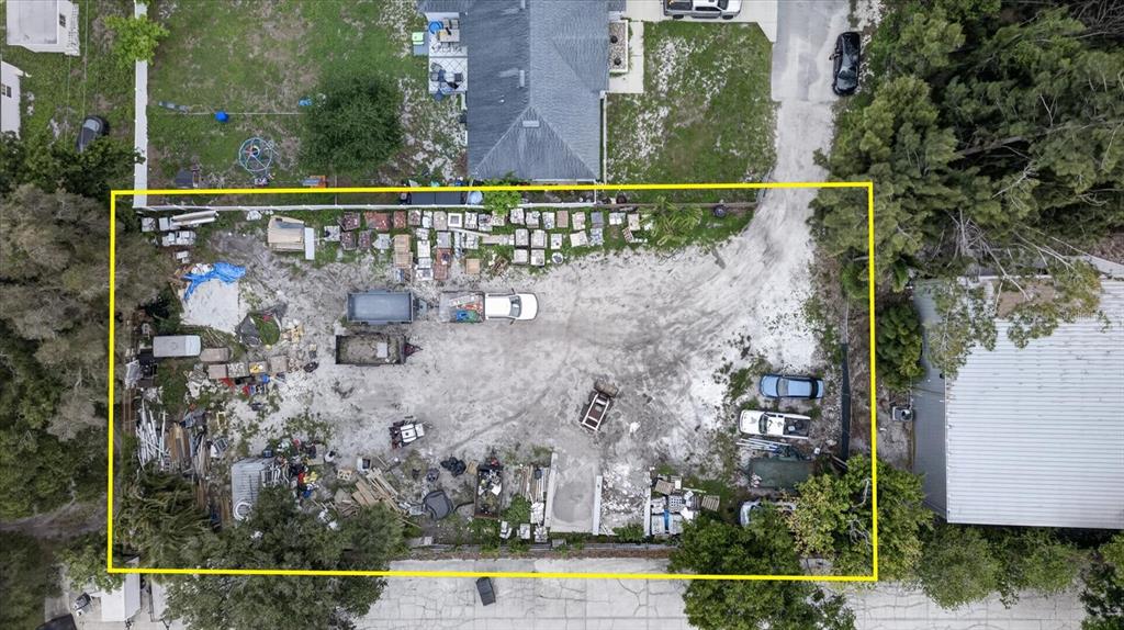 An aerial view shows a large, unpaved lot containing various vehicles, equipment, and scattered materials — 6353 143RD AVENUE, CLEARWATER, FL
