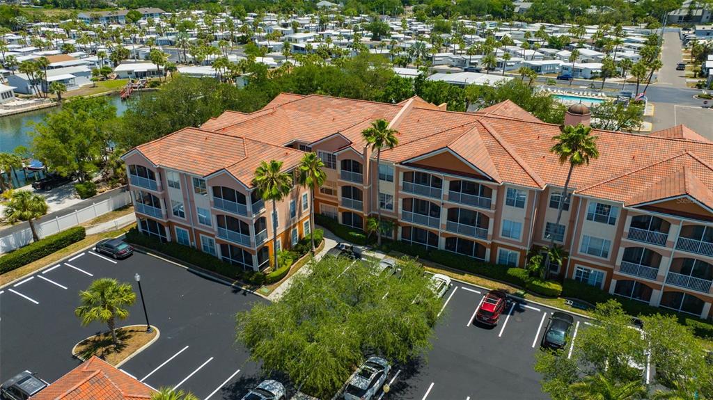 An aerial view shows a multi-story apartment building with a tiled roof and parking lot — 5000 CULBREATH KEY WAY UNIT 1-306, TAMPA, FL