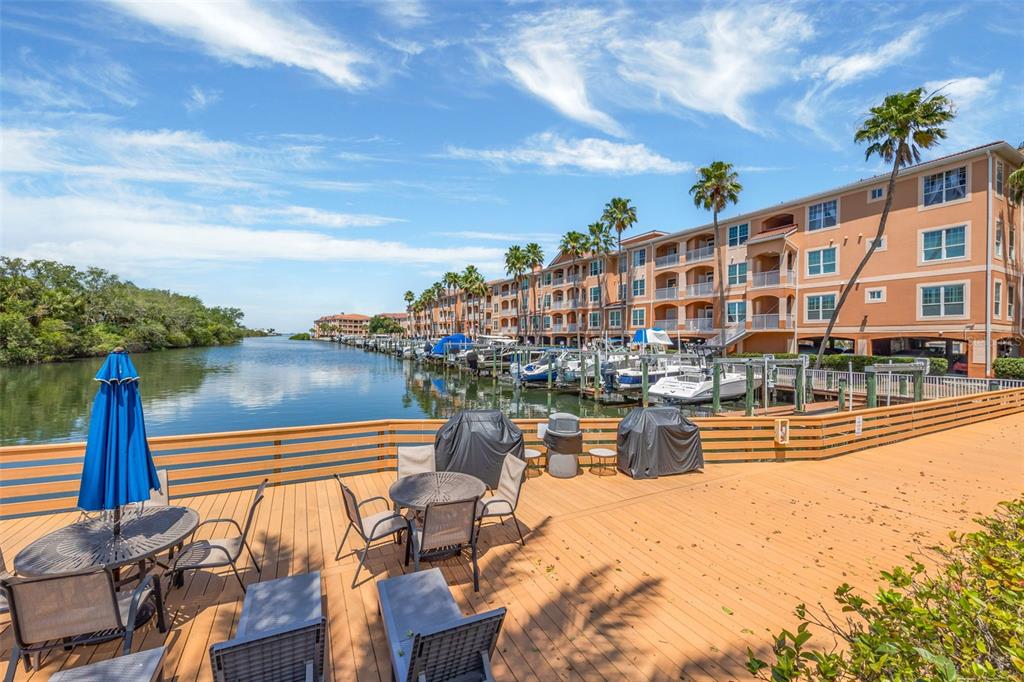 A wooden deck with outdoor furniture overlooks a canal lined with boats and apartment buildings — 5000 CULBREATH KEY WAY UNIT 1-306, TAMPA, FL