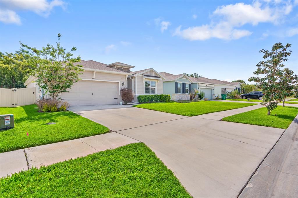 A suburban house with a beige garage, a concrete driveway, and a green lawn — 8362 WHEAT STONE DRIVE, ZEPHYRHILLS, FL