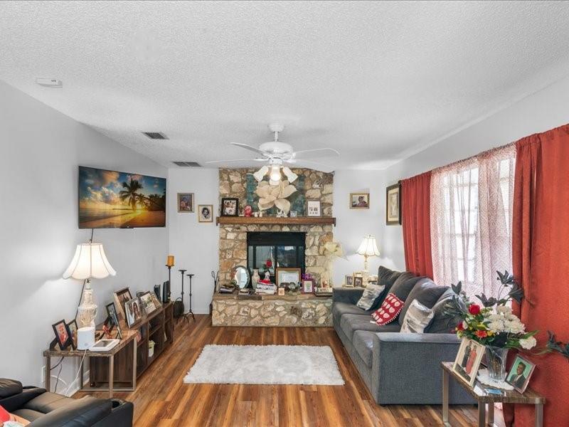 A living room features a stone fireplace, wood flooring, a ceiling fan, and a gray sofa — 1 Westcliffe Lane, Palm Coast FL 32164, PALM COAST, FL