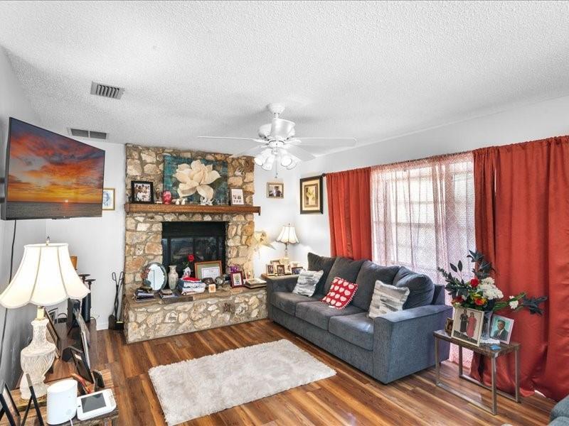 A living room features a stone fireplace, a grey sofa, and wood-look flooring — 1 Westcliffe Lane, Palm Coast FL 32164, PALM COAST, FL