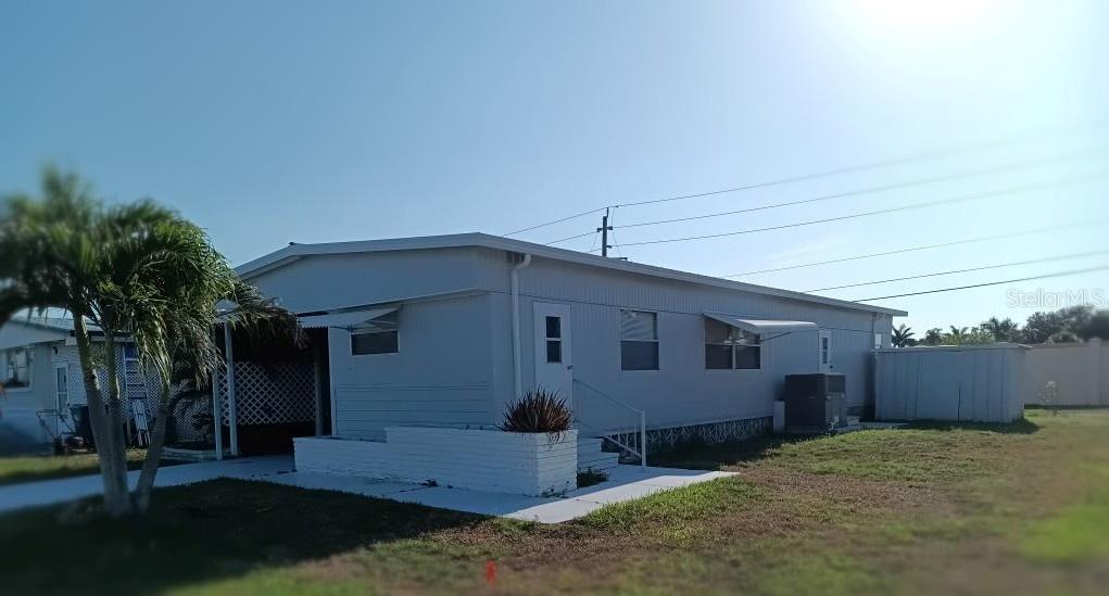 A light-colored mobile home with a white brick planter and a covered carport area — 5031 4TH STREET E, BRADENTON, FL