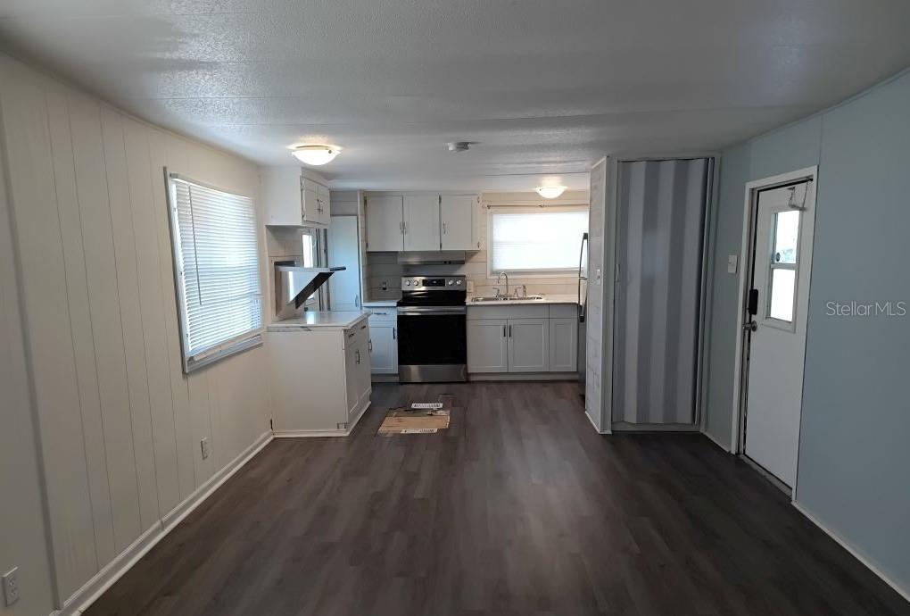 A kitchen with white cabinets, stainless steel appliances, and wood-look flooring in an open space — 5031 4TH STREET E, BRADENTON, FL