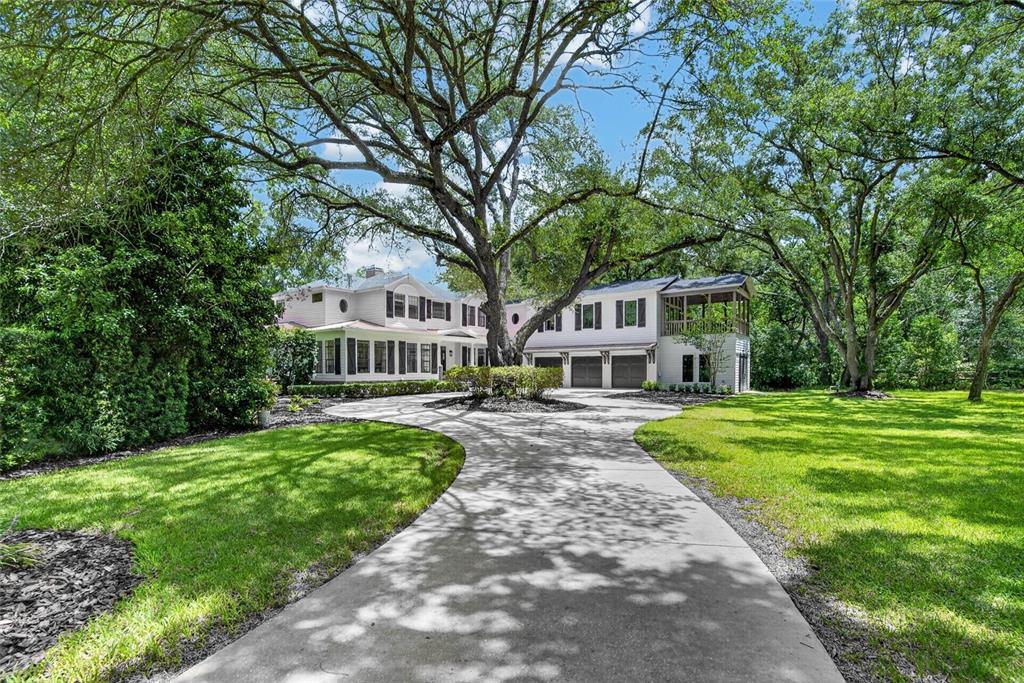 A large two-story house with a circular driveway and mature trees in the front yard — 16317 EMERALD COVE, LUTZ, FL
