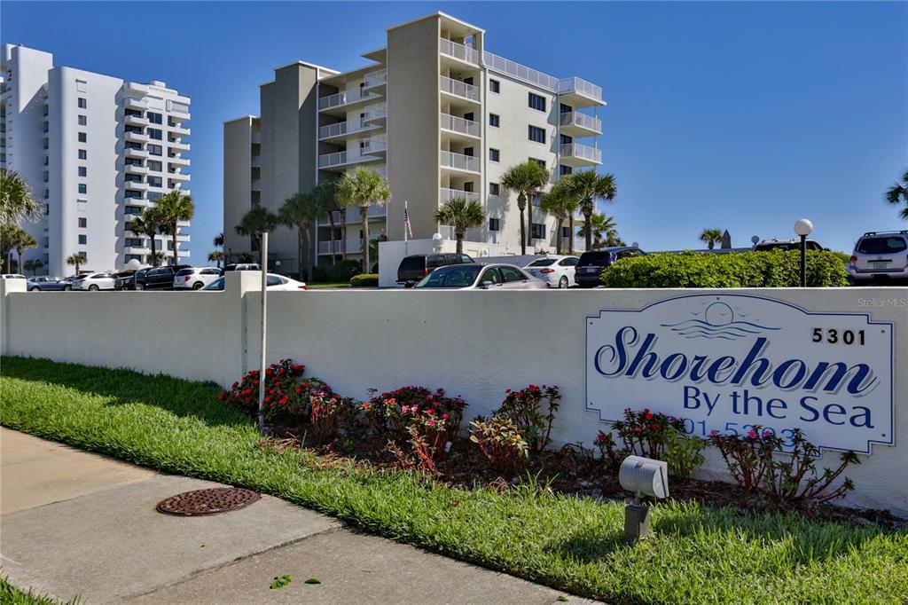 A multi-story apartment building stands behind a white wall with a Shorehom sign — 5301 S ATLANTIC AVENUE UNIT 73, NEW SMYRNA BEACH, FL