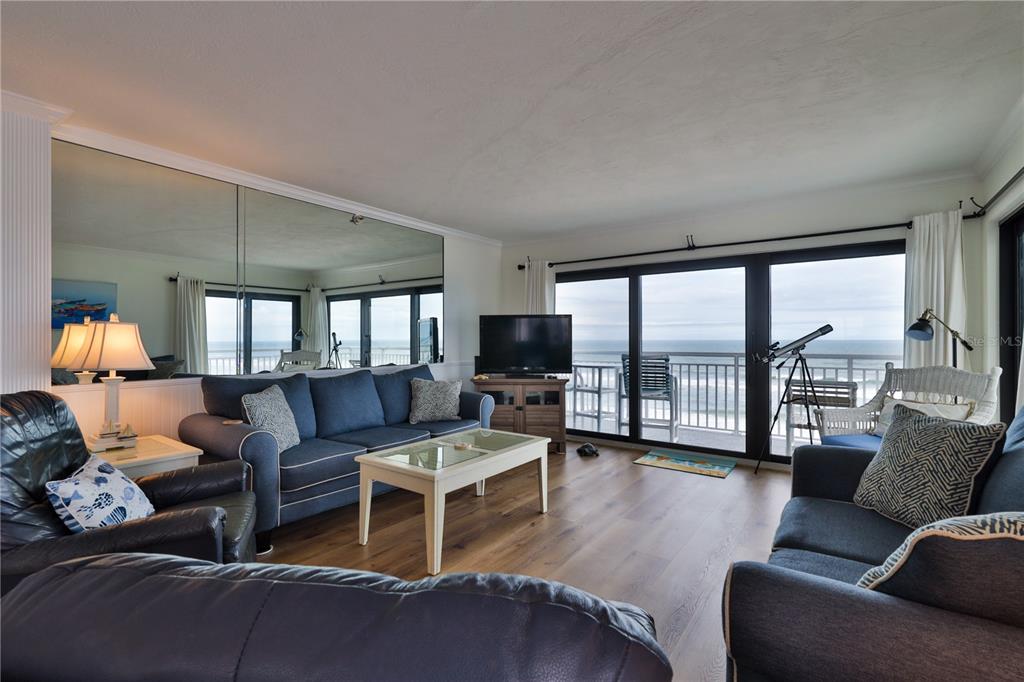 A living room with blue sofas, a coffee table, a large mirror, and ocean views — 5301 S ATLANTIC AVENUE UNIT 73, NEW SMYRNA BEACH, FL