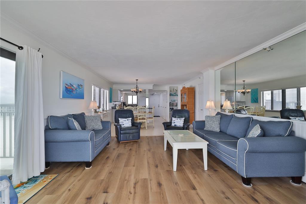 A living room features blue sofas, a white coffee table, and wood-look flooring — 5301 S ATLANTIC AVENUE UNIT 73, NEW SMYRNA BEACH, FL