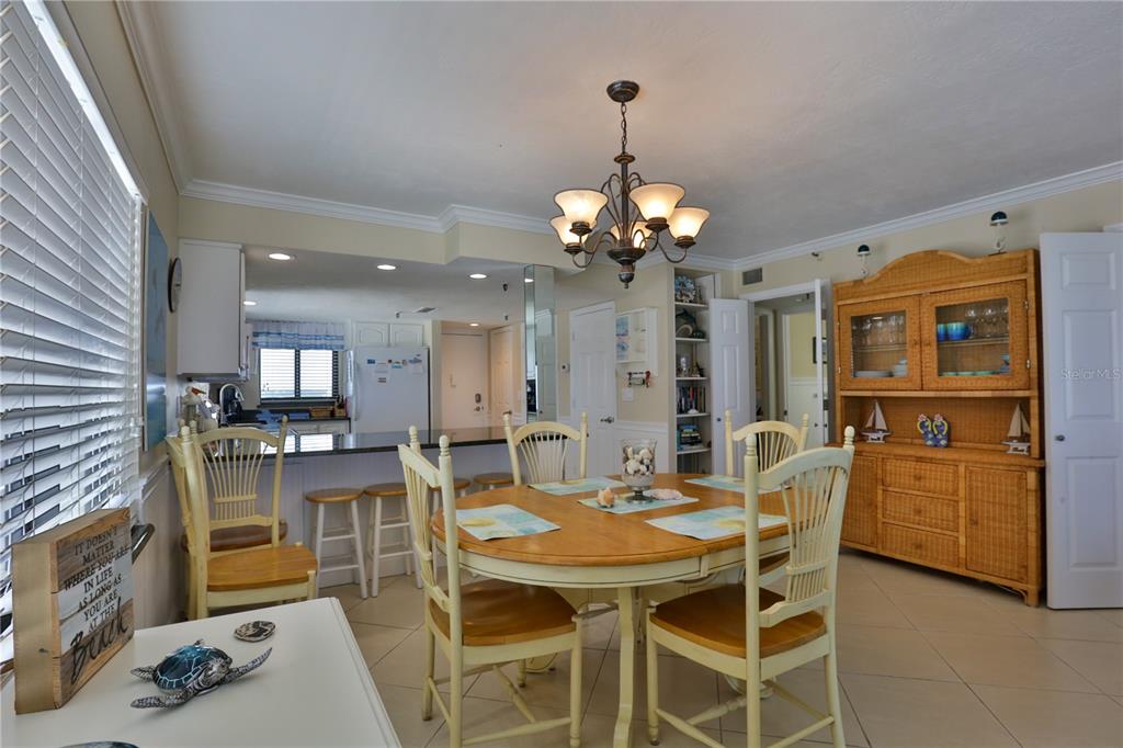 A dining room with a wooden table, chairs, and a hutch, adjacent to a kitchen — 5301 S ATLANTIC AVENUE UNIT 73, NEW SMYRNA BEACH, FL