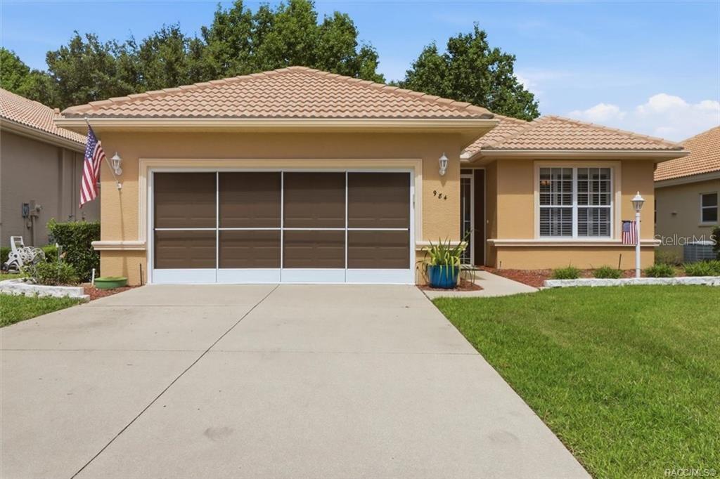 A single-story house with a tan stucco exterior, a brown garage door, and a tiled roof — 984 W SILVER MEADOW LOOP, HERNANDO, FL