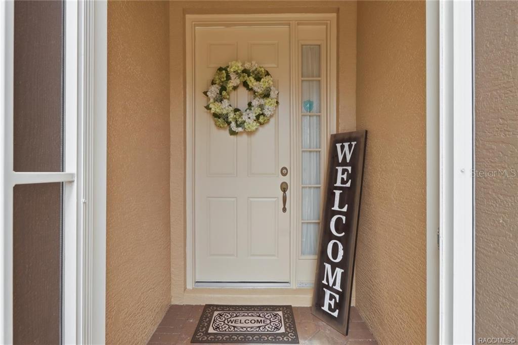 A front entryway features a white door with a wreath, a welcome sign, and a mat — 984 W SILVER MEADOW LOOP, HERNANDO, FL