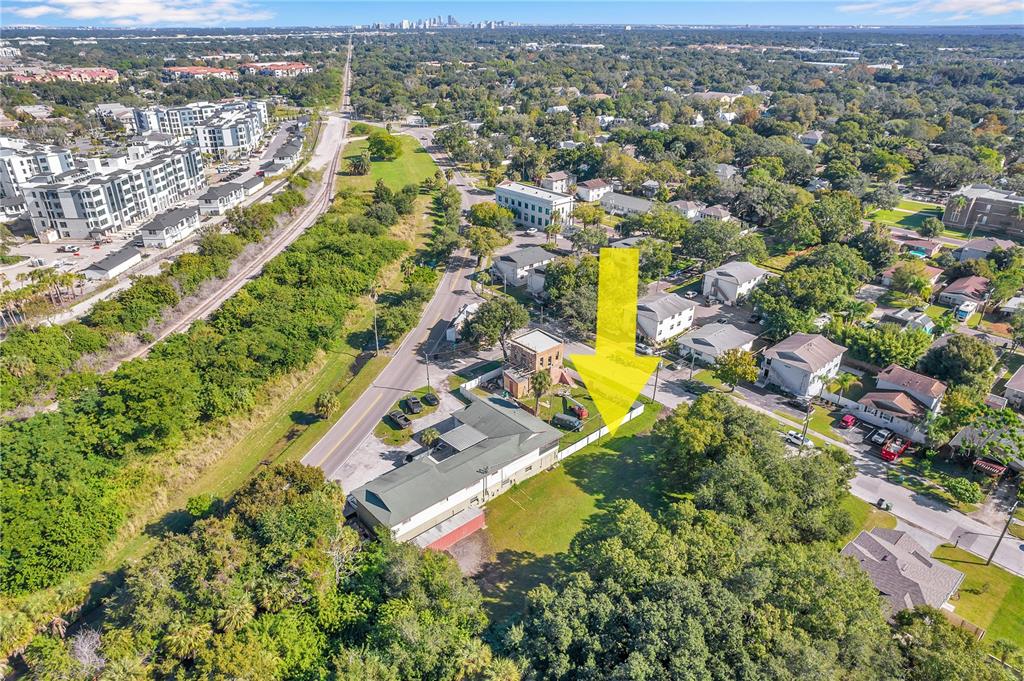 An aerial view shows a commercial building with a fenced yard and a yellow arrow — 7111 S KISSIMMEE STREET, TAMPA, FL