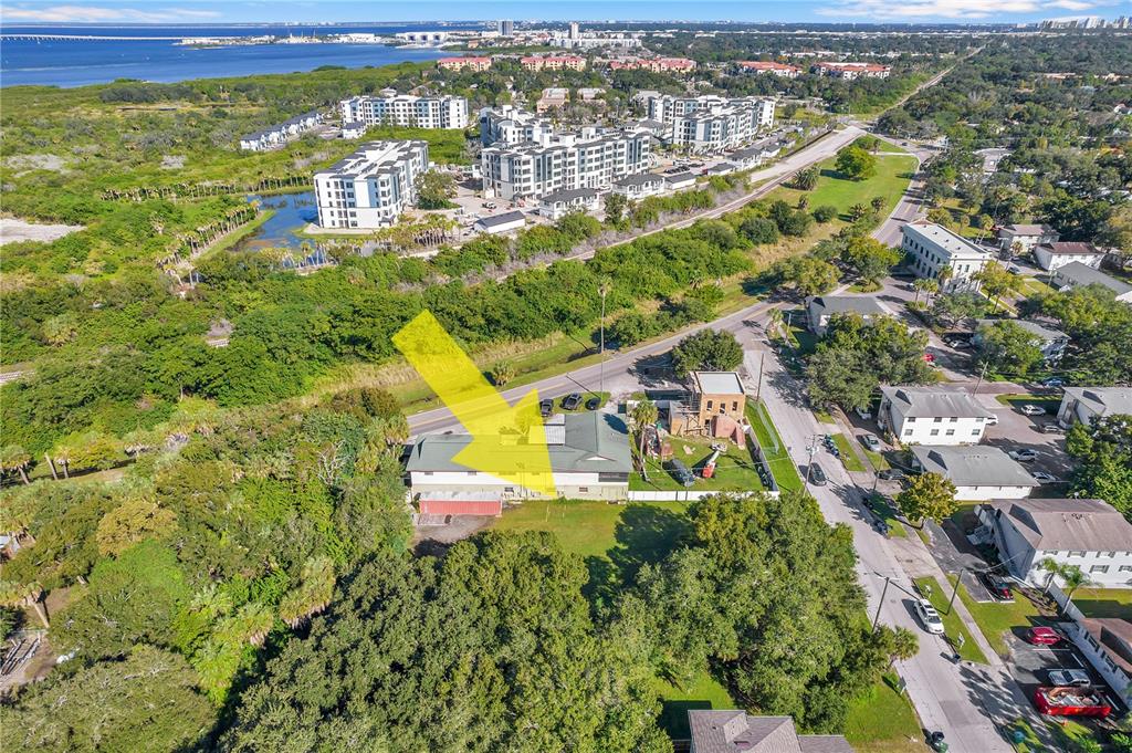 An aerial view shows a building with a green roof surrounded by trees and roads — 7111 S KISSIMMEE STREET, TAMPA, FL