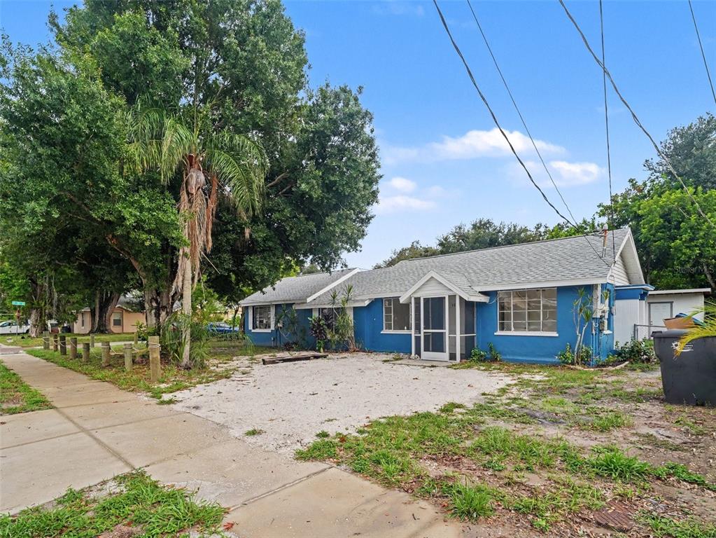 A single-story blue house with a gravel driveway and a screened front porch — 124 26TH AVENUE E UNIT A, BRADENTON, FL
