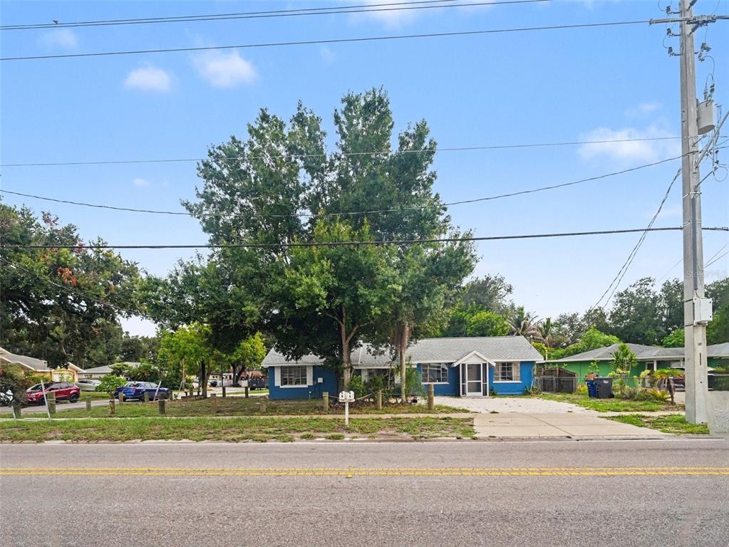 A blue single-story house with a large tree in the front yard faces a road — 124 26TH AVENUE E UNIT A, BRADENTON, FL