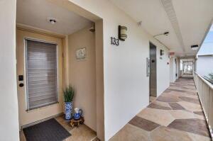 An exterior hallway features a door numbered 133, a potted plant, and tiled flooring — 133 Capri # C, Delray Beach FL 33484, DELRAY BEACH, FL