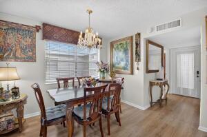 A dining room features a wooden table, six chairs, a chandelier, and wall art — 133 Capri # C, Delray Beach FL 33484, DELRAY BEACH, FL
