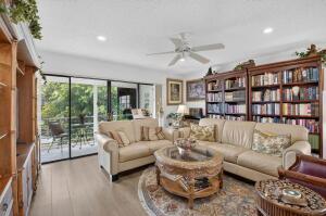 A living room features a beige sofa, a round coffee table, and large wooden bookshelves — 133 Capri # C, Delray Beach FL 33484, DELRAY BEACH, FL