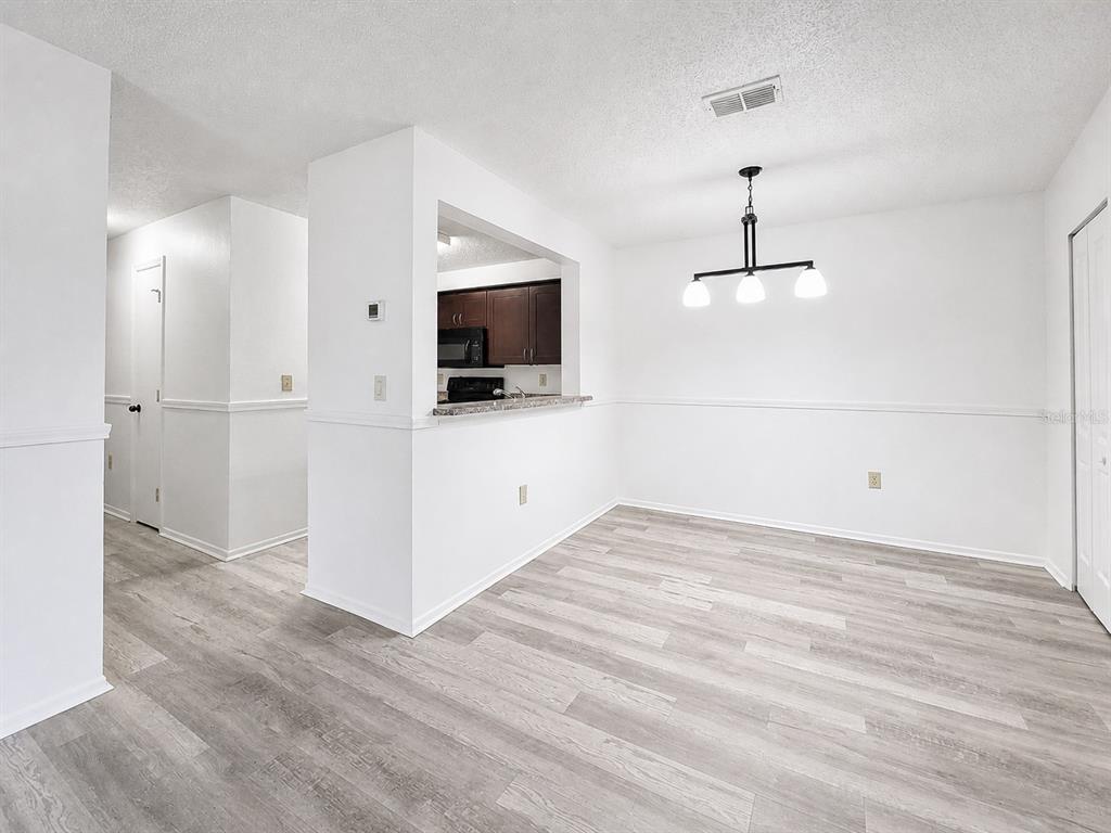 A dining area with light wood-look flooring, white walls, and a pass-through to the kitchen — 3705 SW 27TH STREET UNIT 921, GAINESVILLE, FL