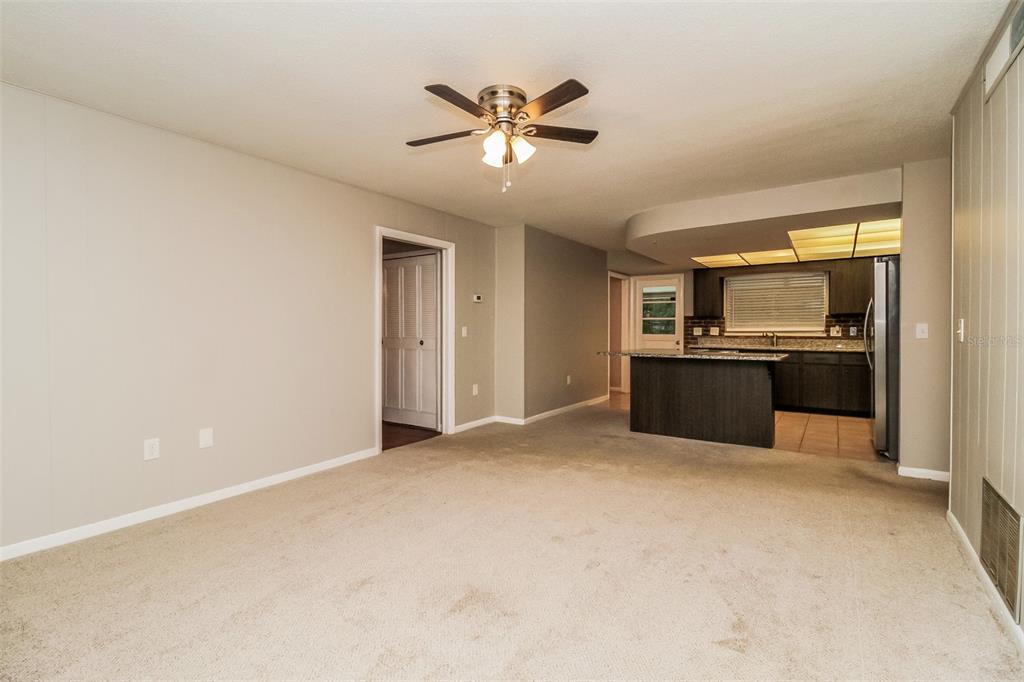 A carpeted living room opens to a kitchen with dark cabinets and a granite island — 745 LITTLE WEKIVA CIRCLE, ALTAMONTE SPRINGS, FL