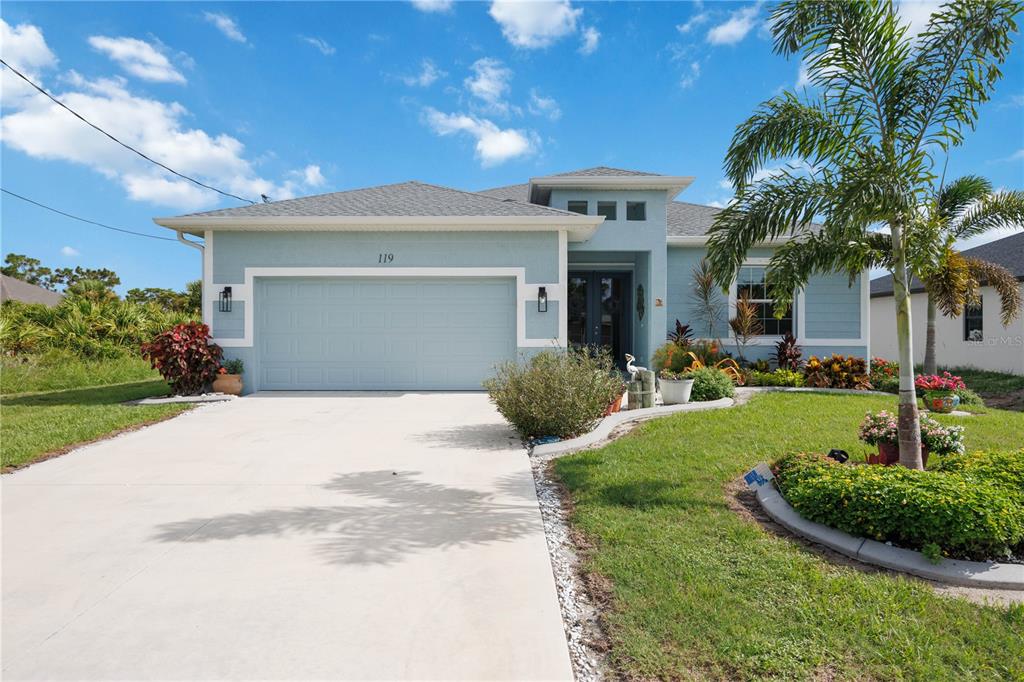 A light blue single-story house with a two-car garage and a palm tree in front — 119 GREEN OAK PARK, ROTONDA WEST, FL