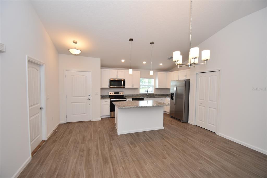 A kitchen with white cabinets, granite countertops, stainless steel appliances, and wood-look flooring — 19 ETHEL LANE, PALM COAST, FL