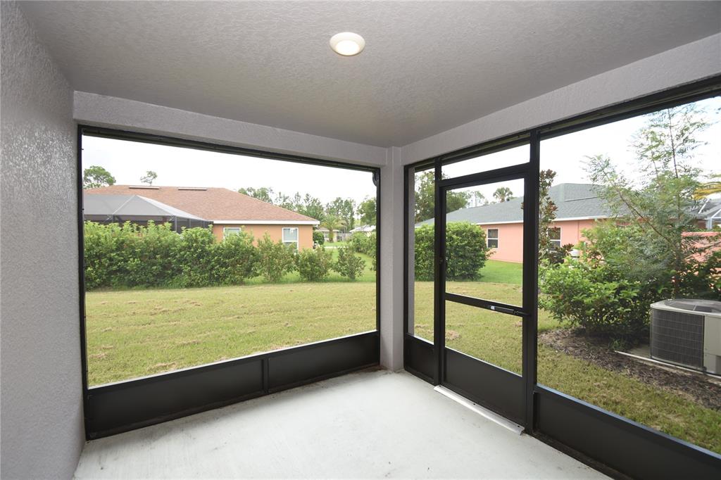 A screened-in porch with a concrete floor, a ceiling light, and views of a backyard — 19 ETHEL LANE, PALM COAST, FL