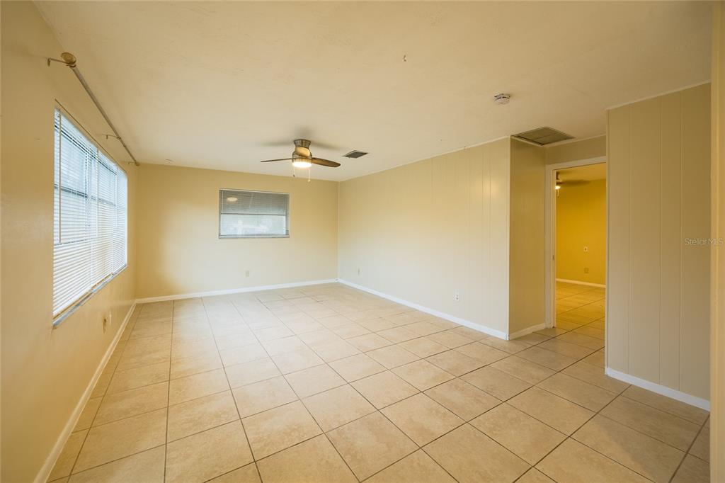 An empty room with beige walls, tiled flooring, a ceiling fan, and two windows — 400 S METEOR AVENUE, CLEARWATER, FL