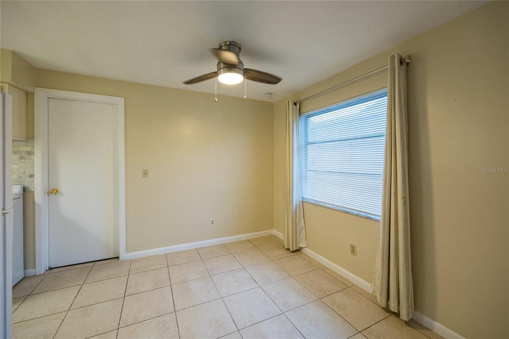 An empty dining area features beige walls, tile flooring, a ceiling fan, and a window — 400 S METEOR AVENUE, CLEARWATER, FL