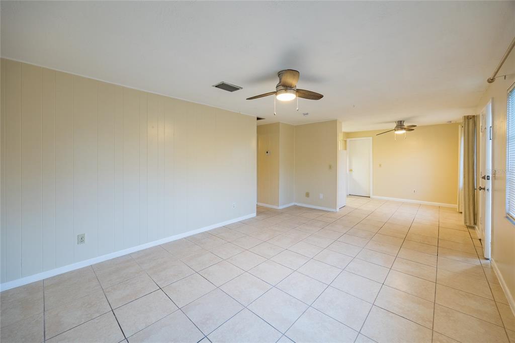 An empty room with beige paneled walls, tiled floors, and two ceiling fans — 400 S METEOR AVENUE, CLEARWATER, FL