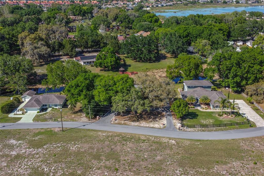 An aerial view shows two houses with driveways surrounded by trees and a nearby lake — 5308 COUNTY ROAD 122, WILDWOOD, FL