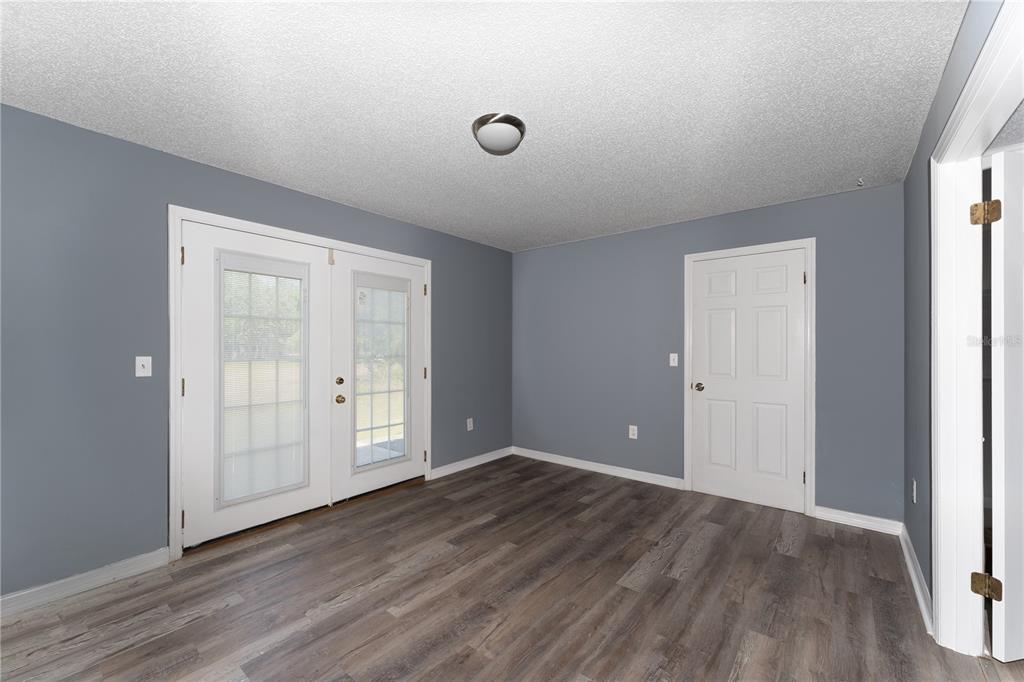 An empty room with gray walls, wood-look flooring, a ceiling light, and white doors — 5308 COUNTY ROAD 122, WILDWOOD, FL