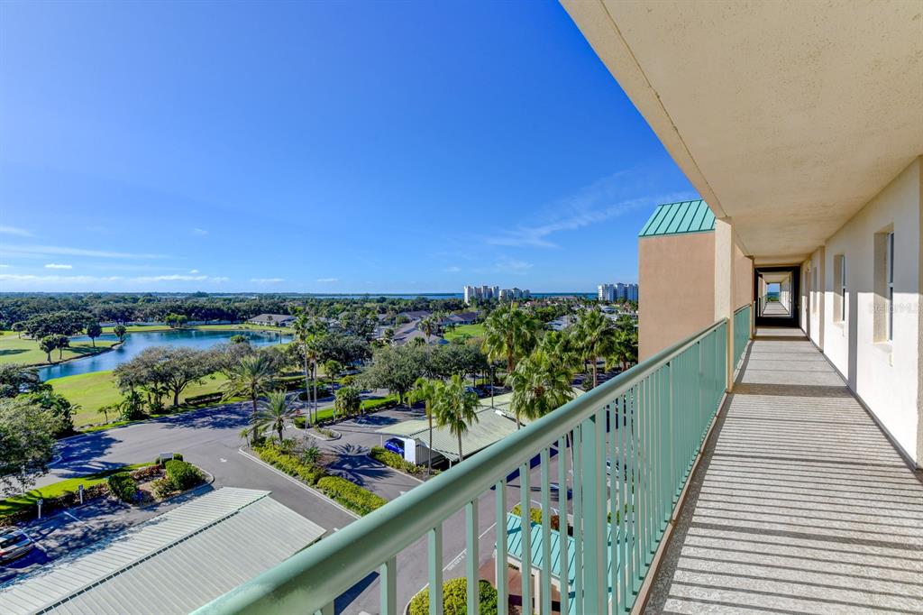 An elevated outdoor walkway with a teal railing overlooks a parking lot, pond, and trees — 2320 TERRA CEIA BAY BOULEVARD UNIT 811, PALMETTO, FL