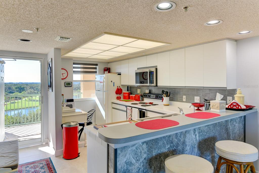 A kitchen features white cabinets, a breakfast bar, and a balcony overlooking a golf course — 2320 TERRA CEIA BAY BOULEVARD UNIT 811, PALMETTO, FL
