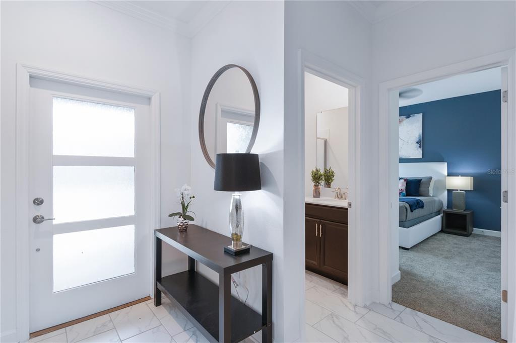 A white entryway features a console table, a mirror, and doorways leading to a bathroom and bedroom — 1060 LEADER STREET, DAVENPORT, FL