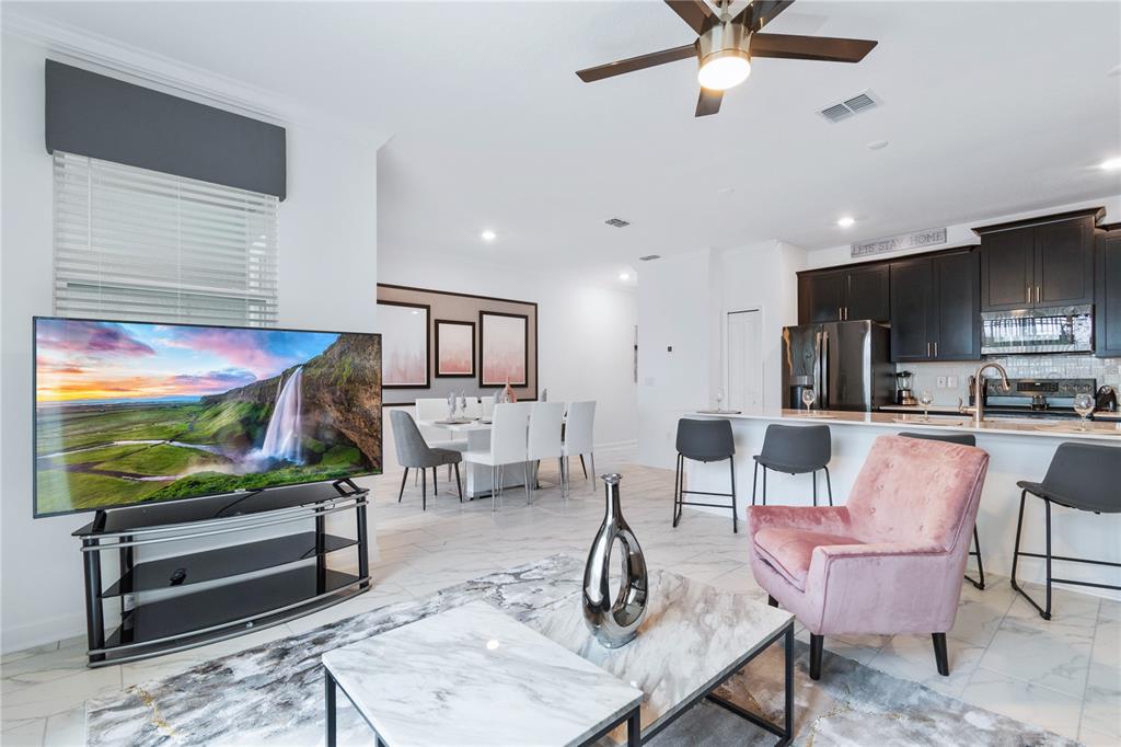 A modern open-concept living room and kitchen feature marble-look tile floors and dark cabinetry — 1060 LEADER STREET, DAVENPORT, FL